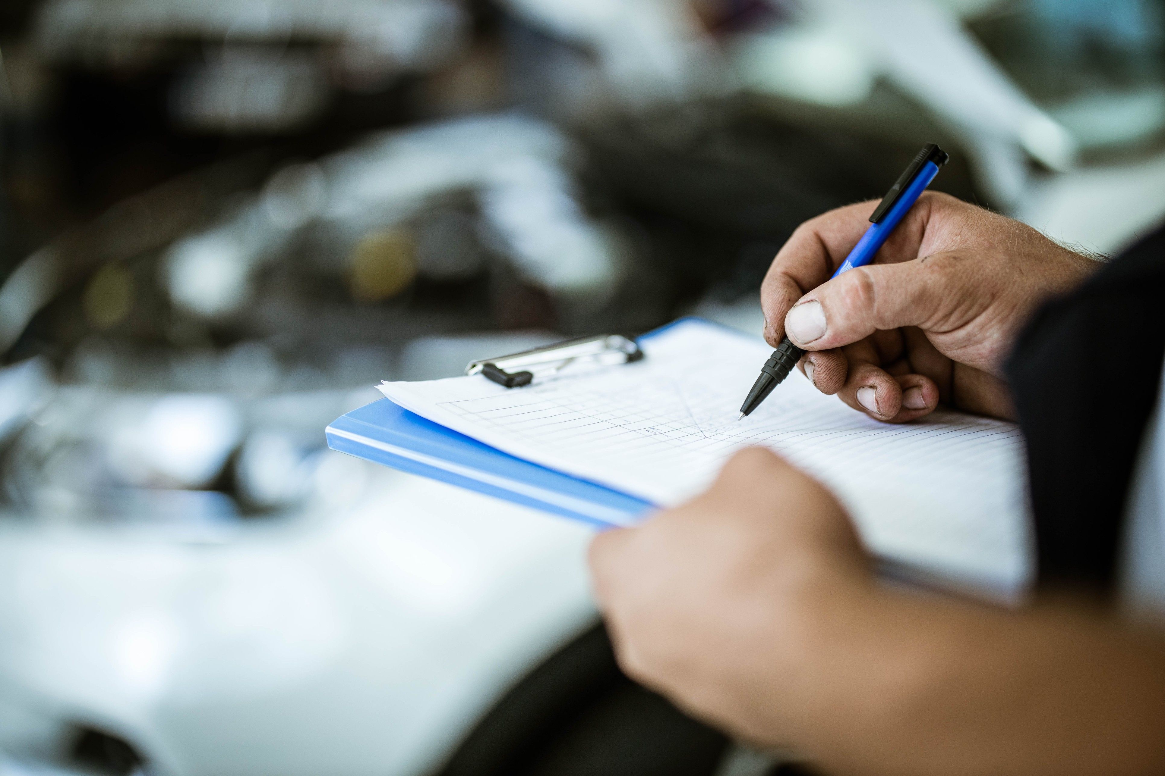 A close up of  hand checking things off a list on a clipboard.