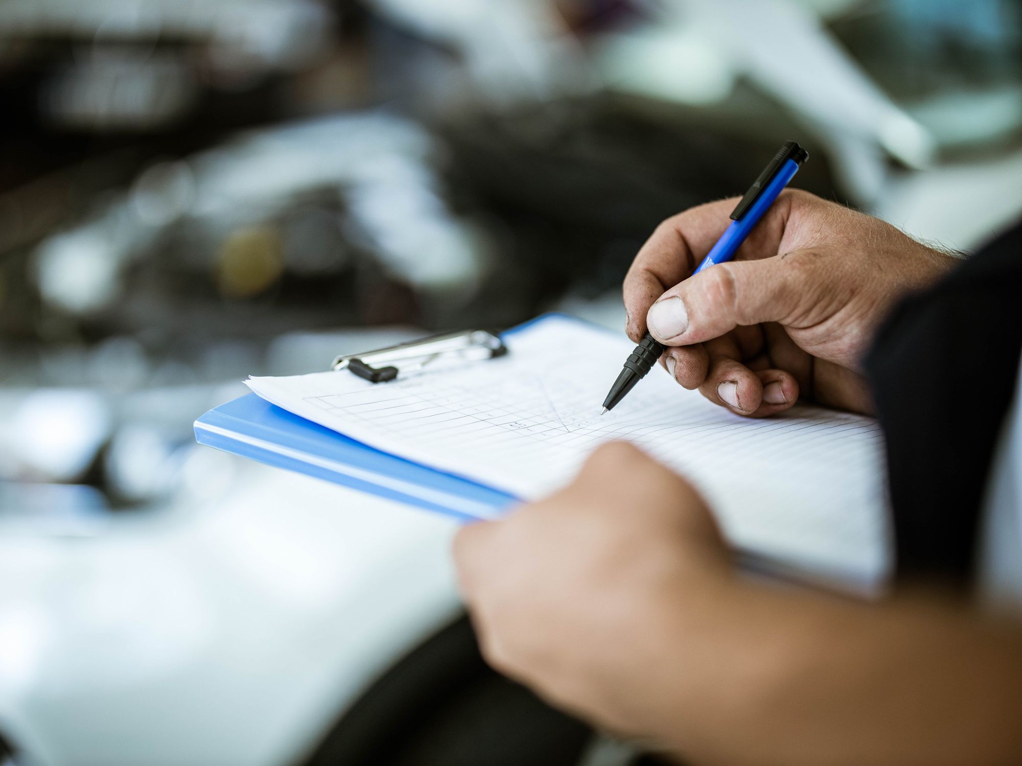 A close up of  hand checking things off a list on an indescript clipboard.