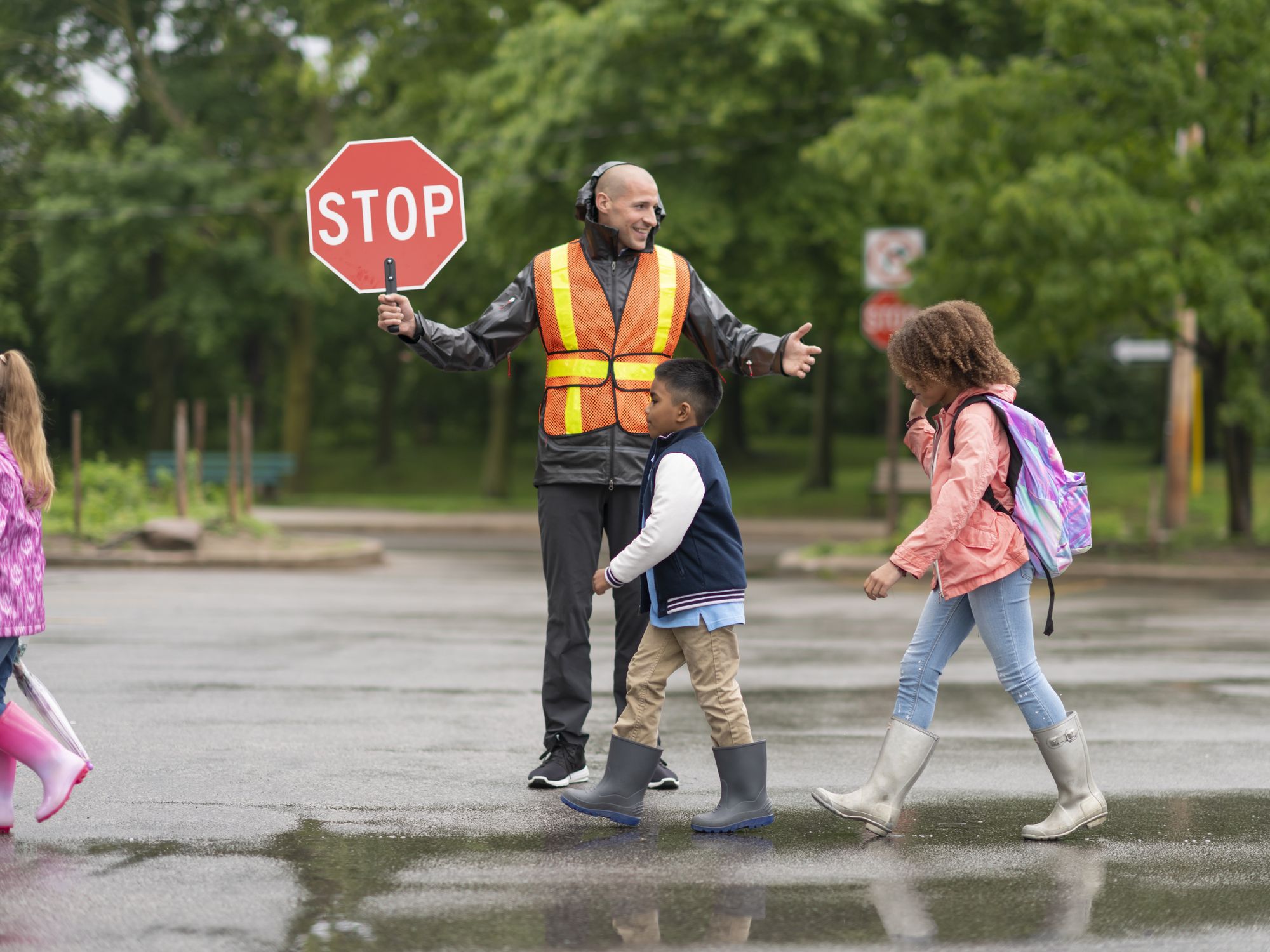 A crossing guard stops traffic as children cross the street