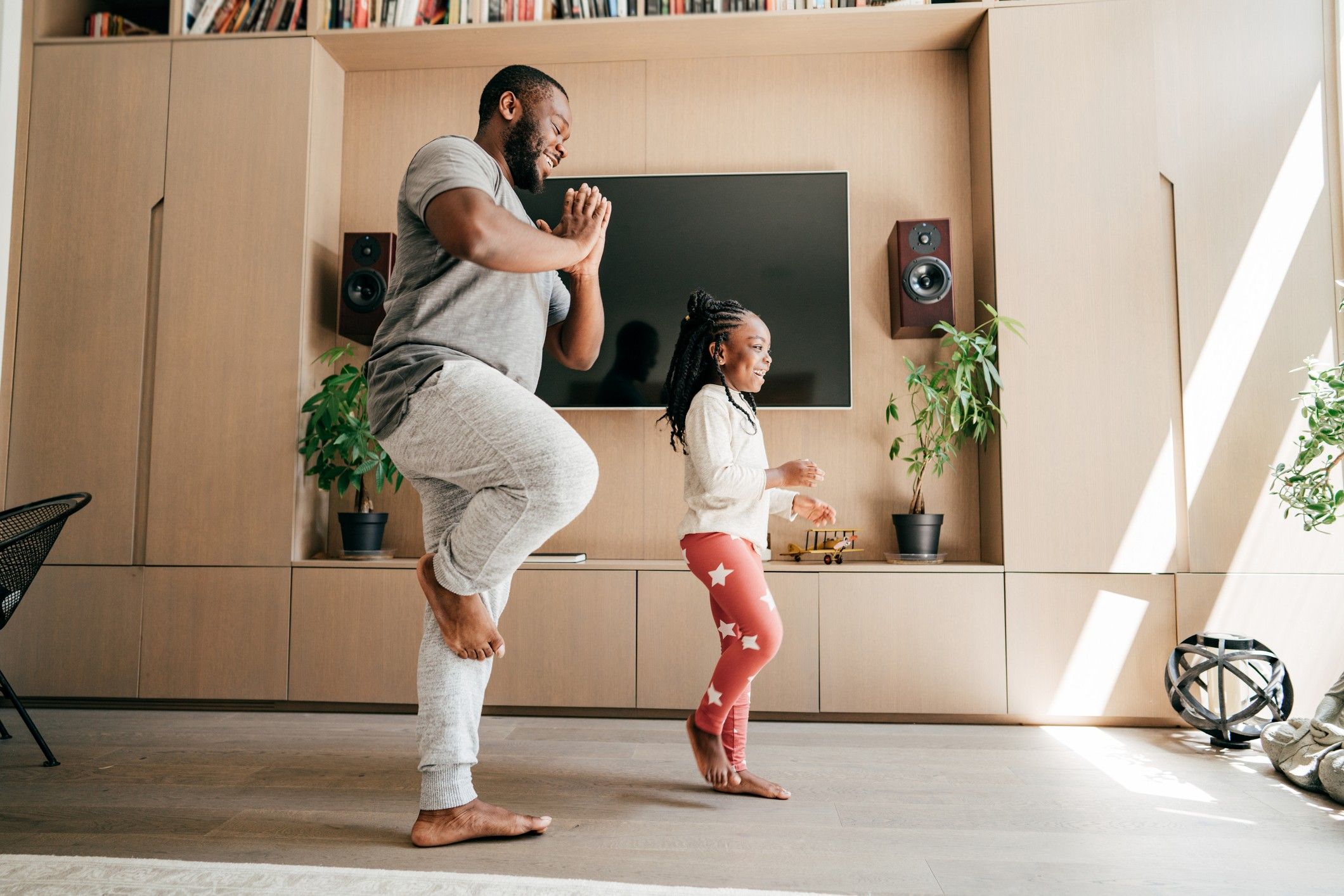 A dad and daughter practicing yoga in the living room.