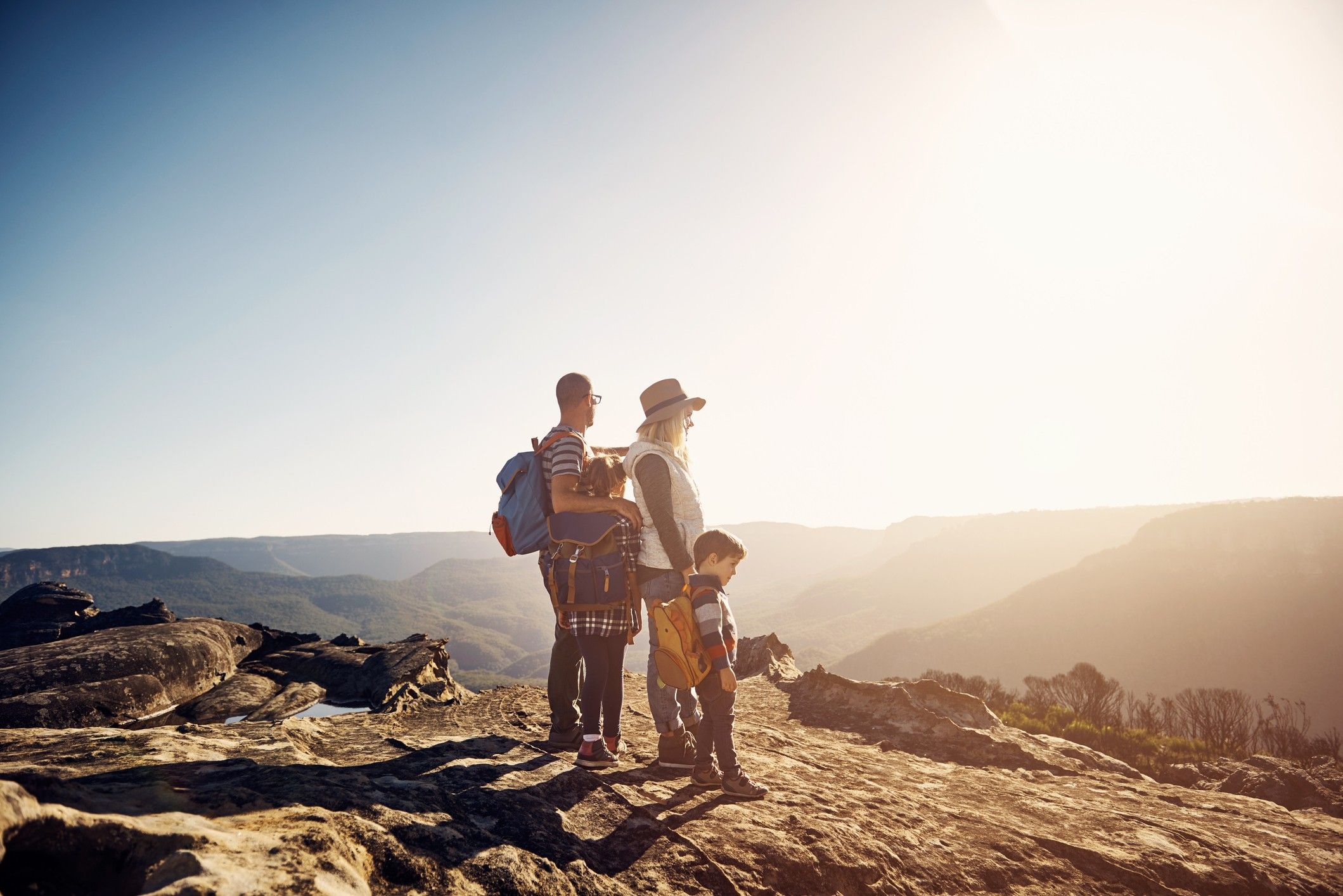 A family of four stands on top of a mountain.
