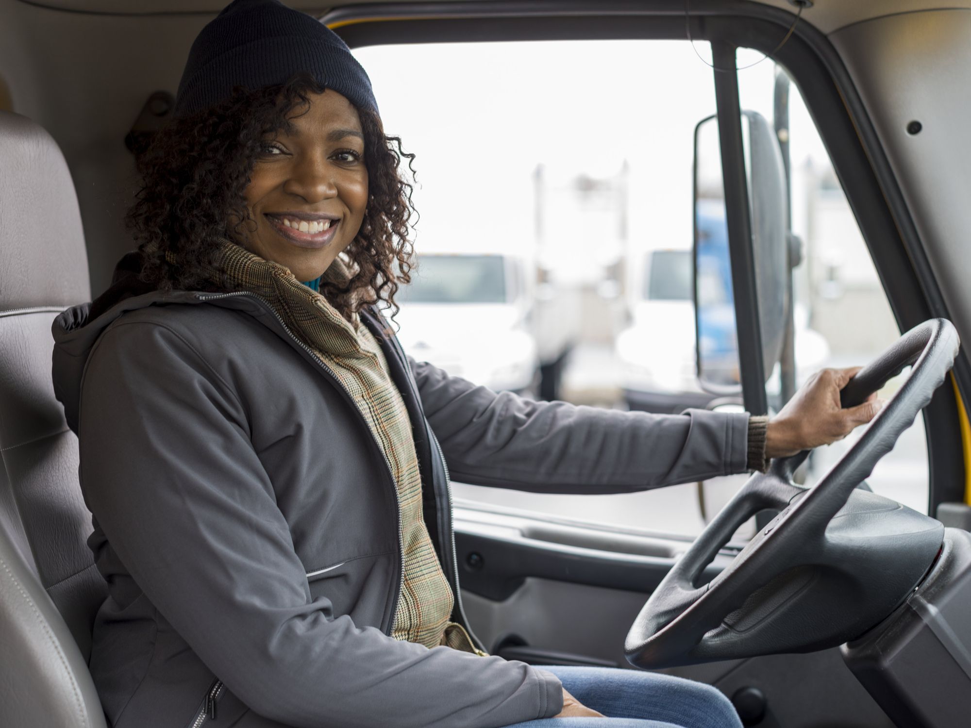 A female driver smiles behind the wheel.