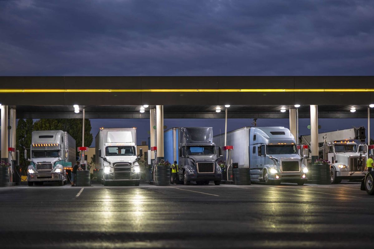 A line of semi-trucks lined up at a fueling station.