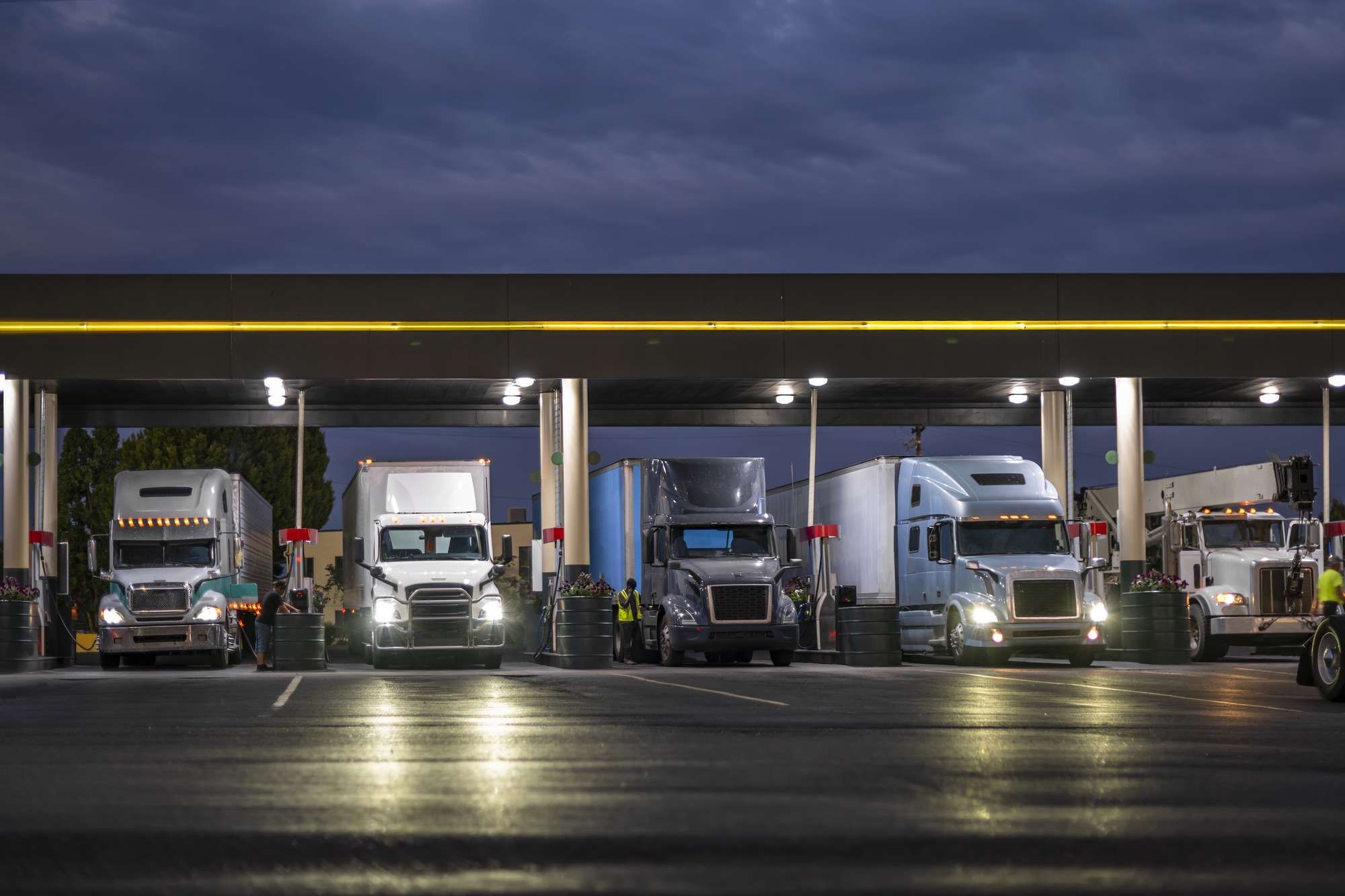 A line of semi-trucks lined up at a fueling station.