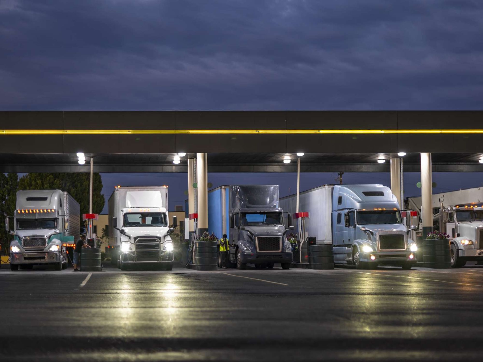 A line of semi-trucks lined up at a fueling station.