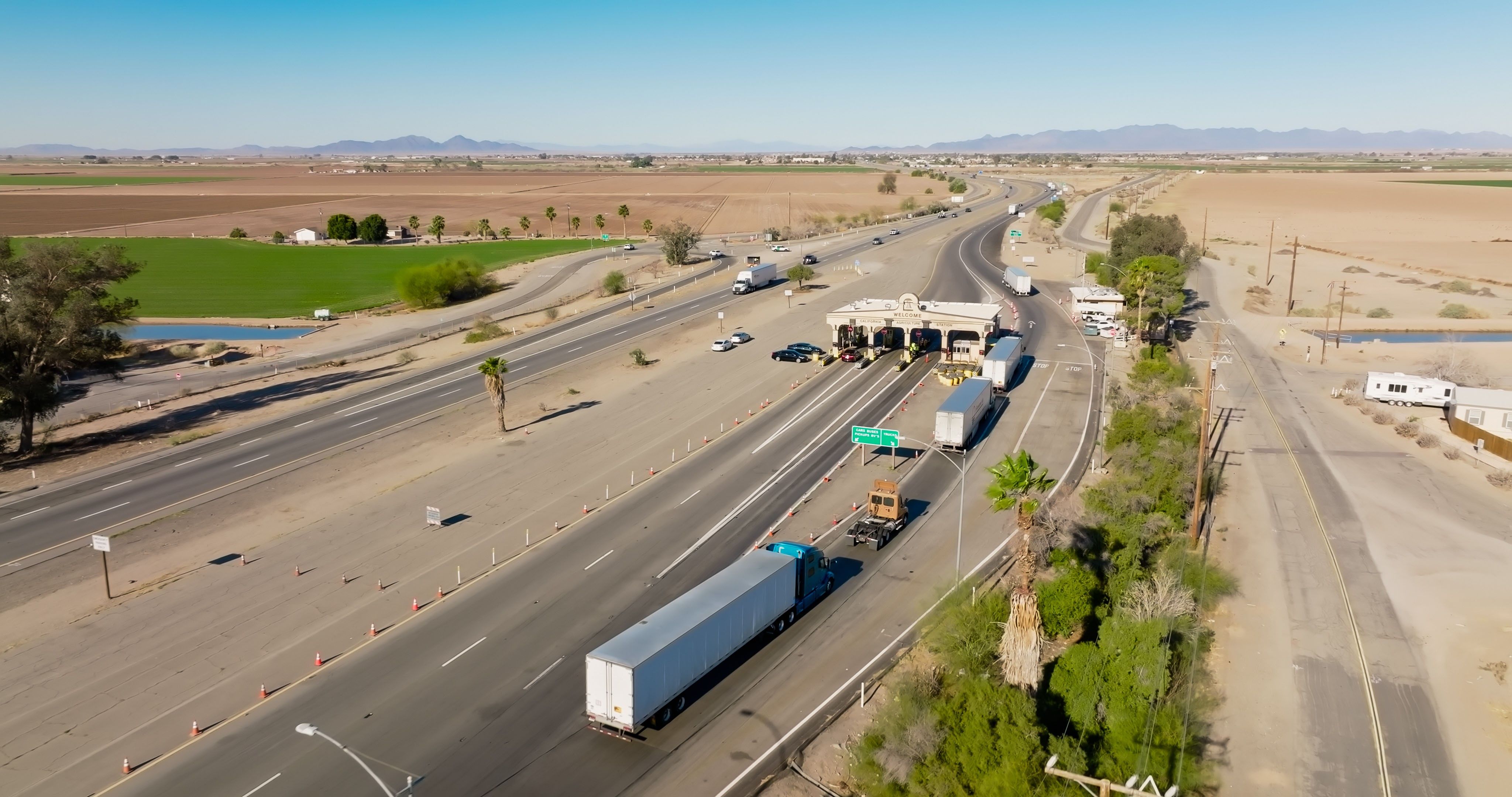 A line of semi trucks wait at an inspection station in California.