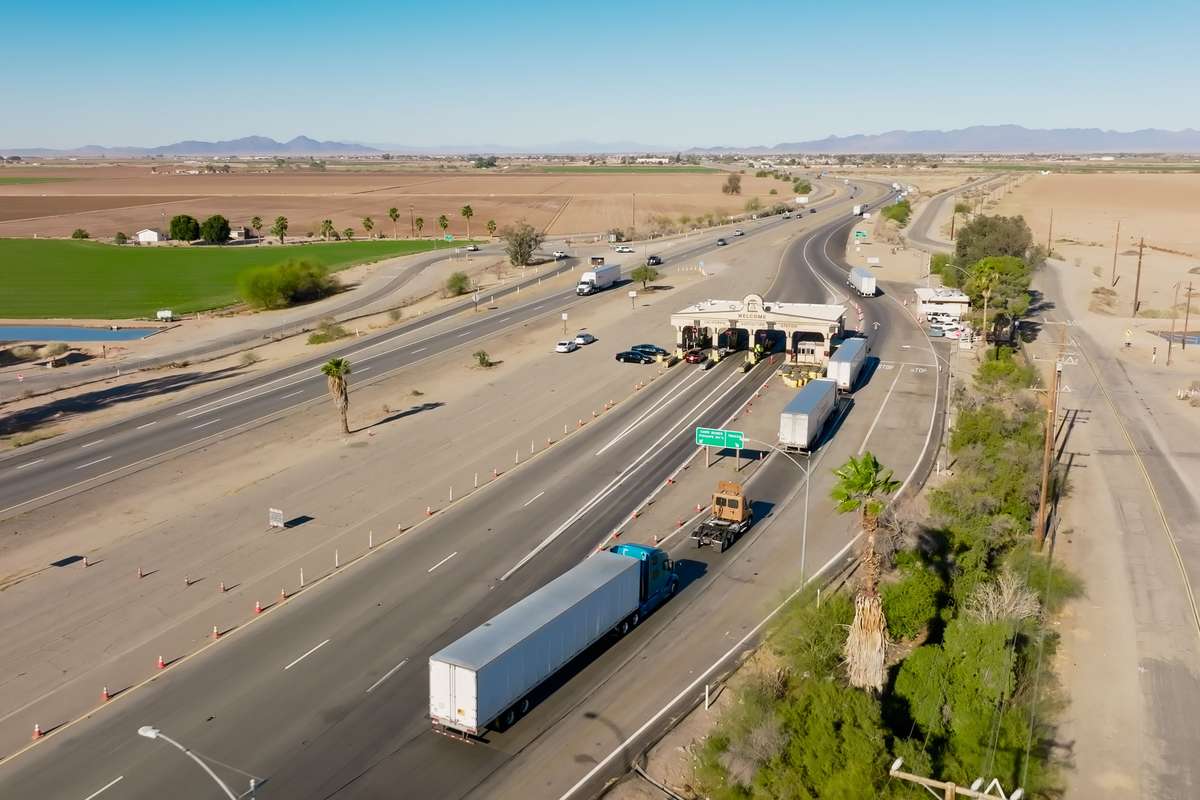 A line of semi trucks wait at an inspection station in California.