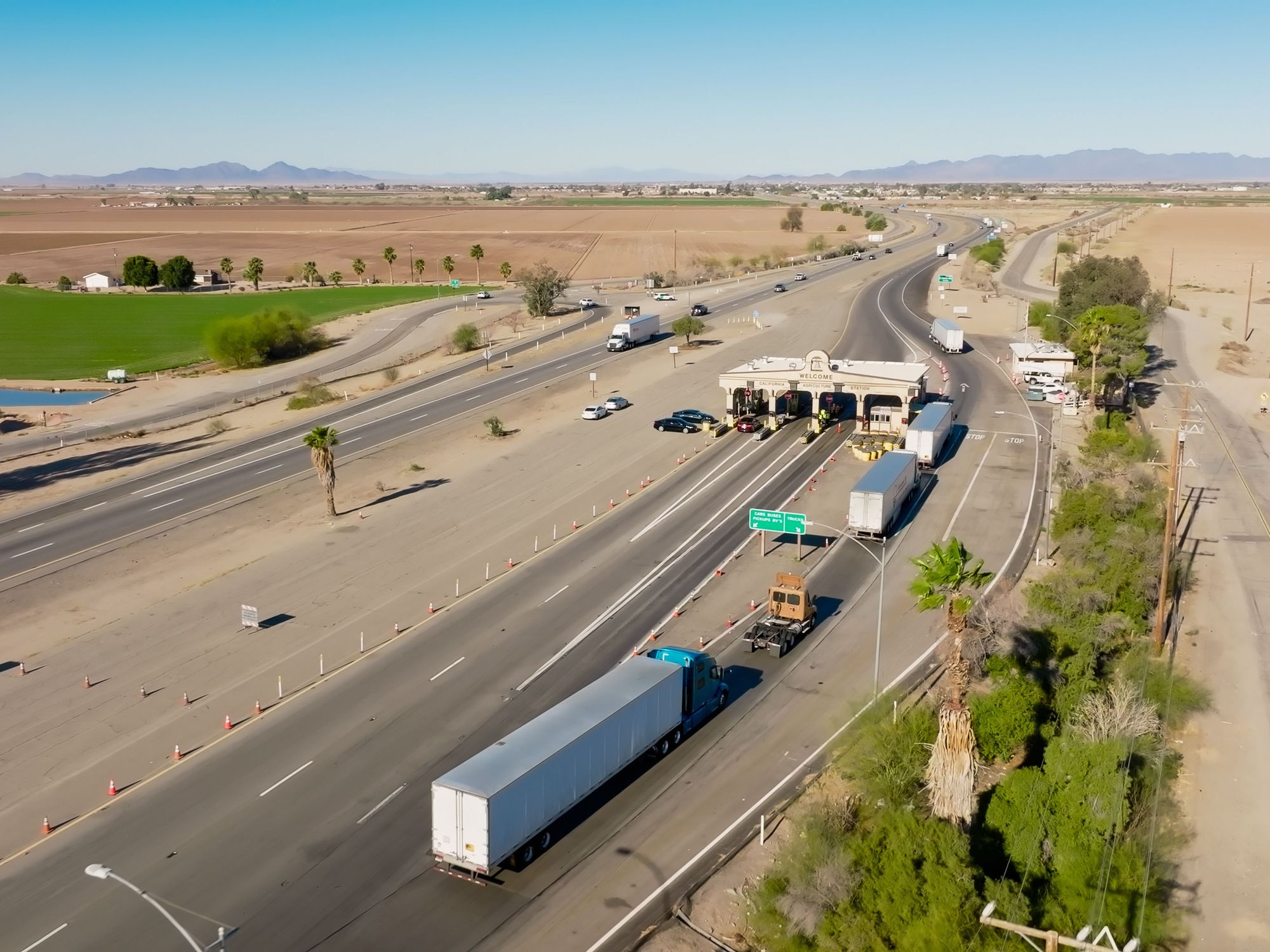 A line of semi trucks wait at an inspection station in California.