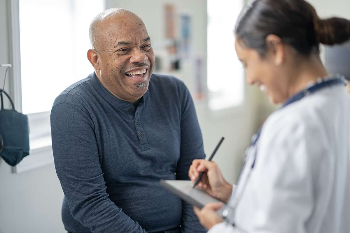 A man in a blue sweater talks to a female doctor.