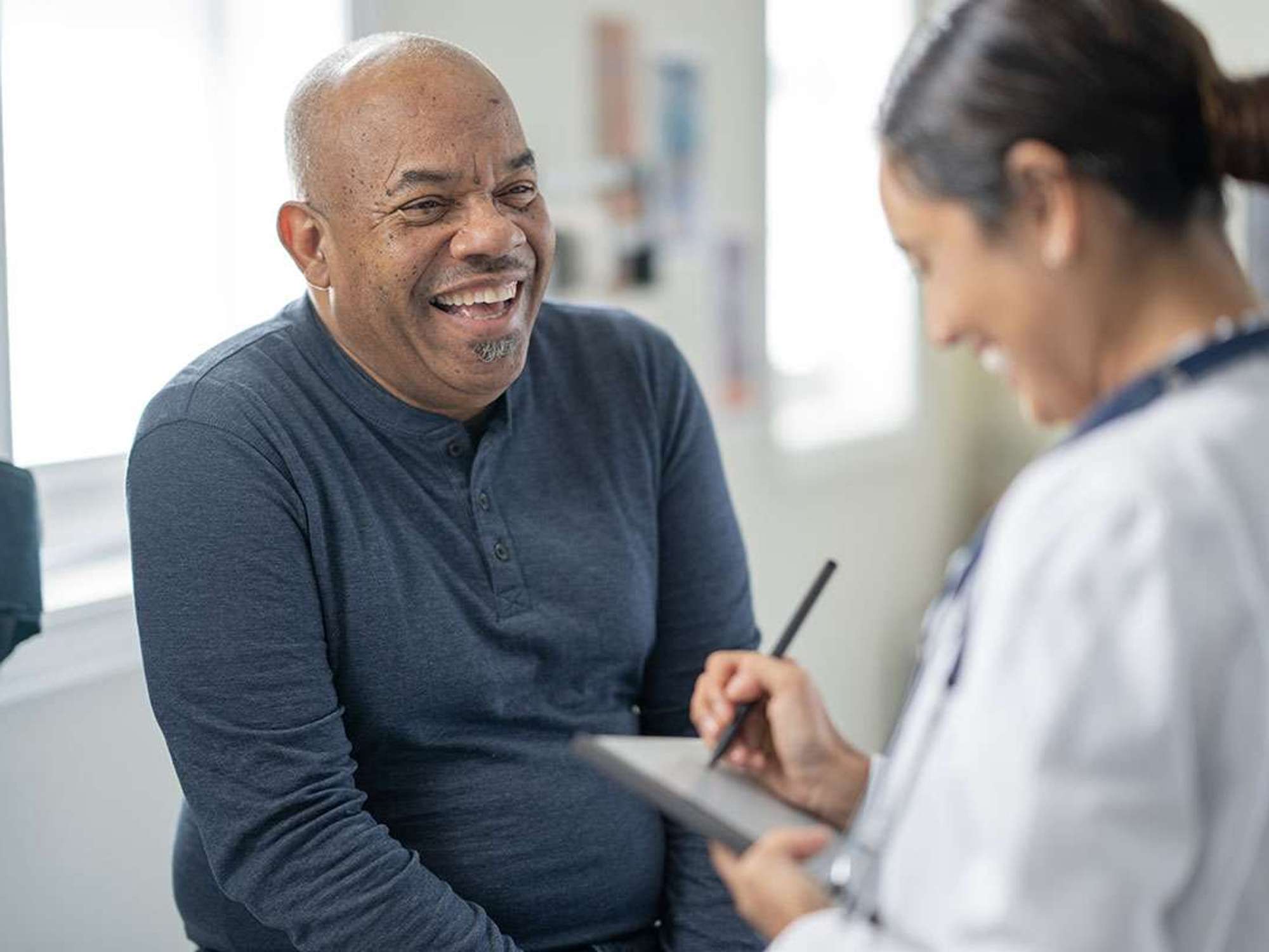 A man in a blue sweater talks to a female doctor.