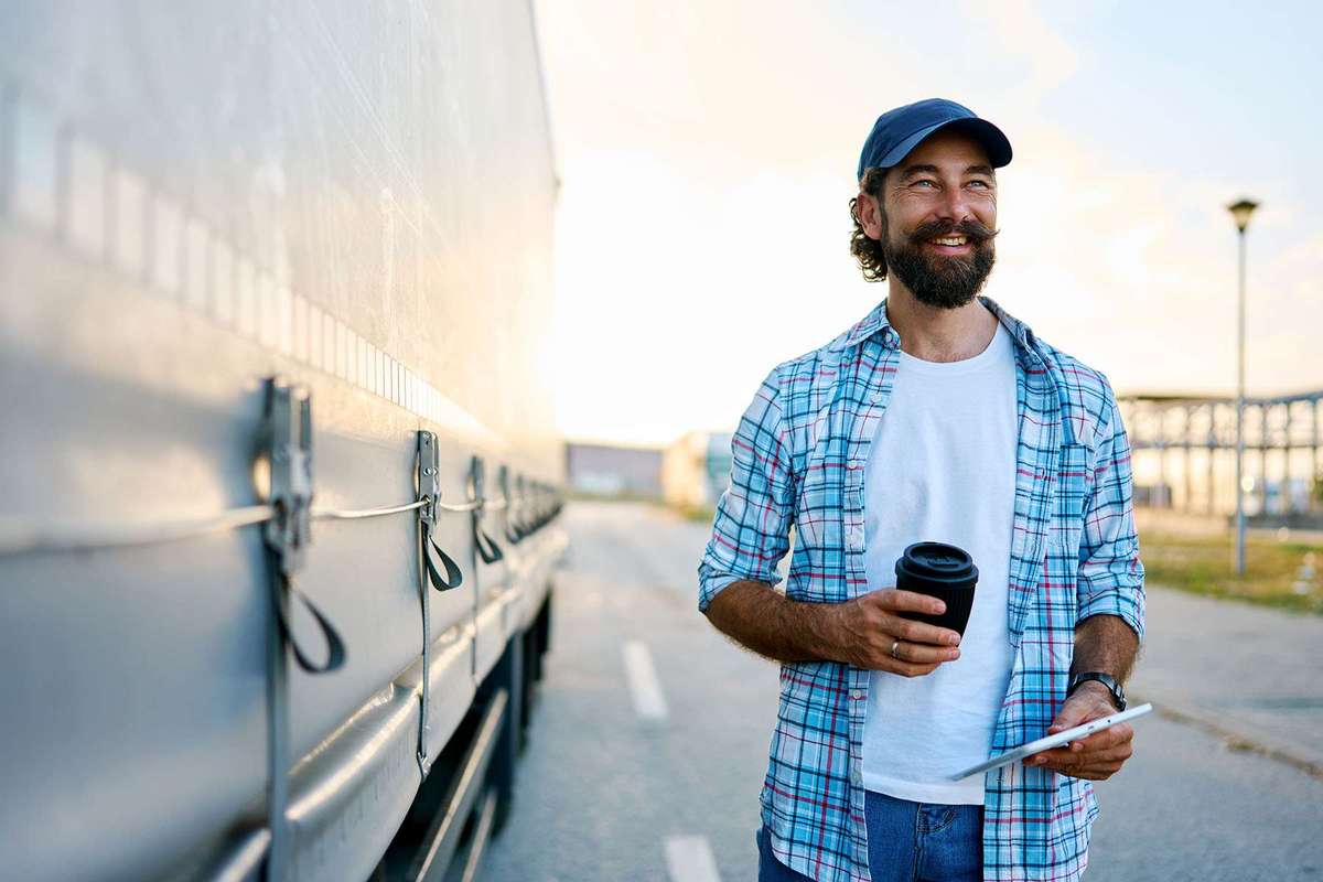 A man walks in a parking lot next to a semi-truck.