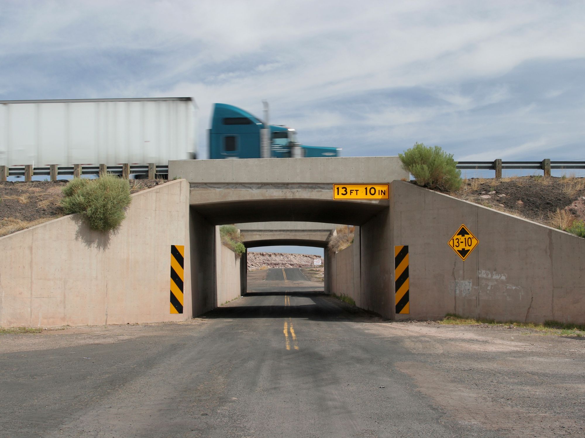 A semi truck drives over a bridge with 13 ft 10 in clearance.