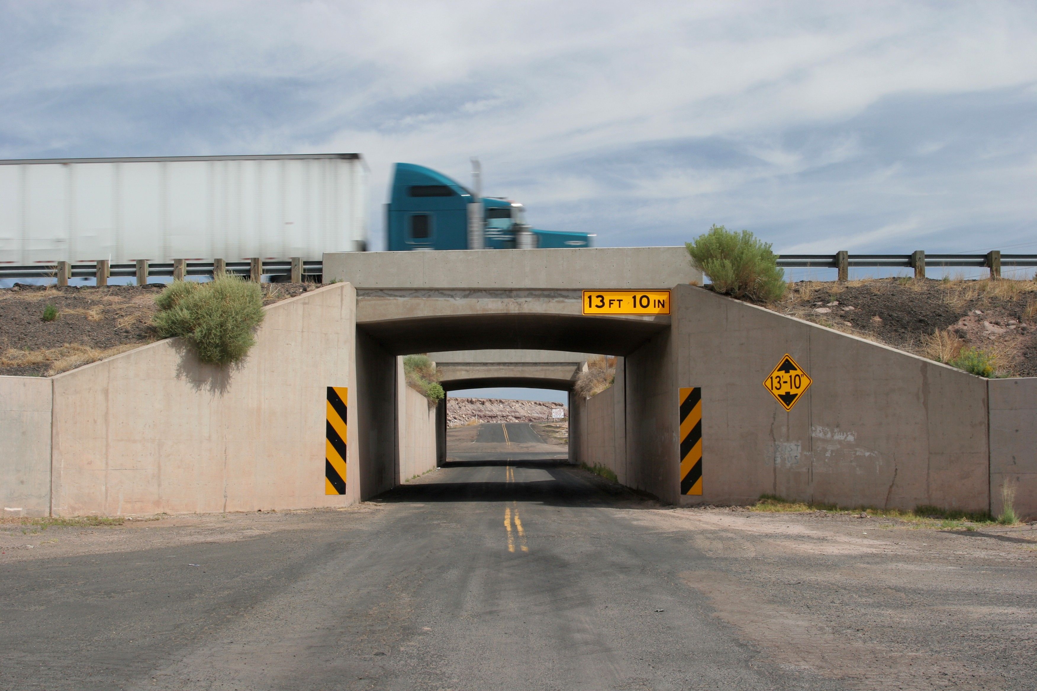 A semi truck drives over a bridge with 13 ft 10 in clearance.