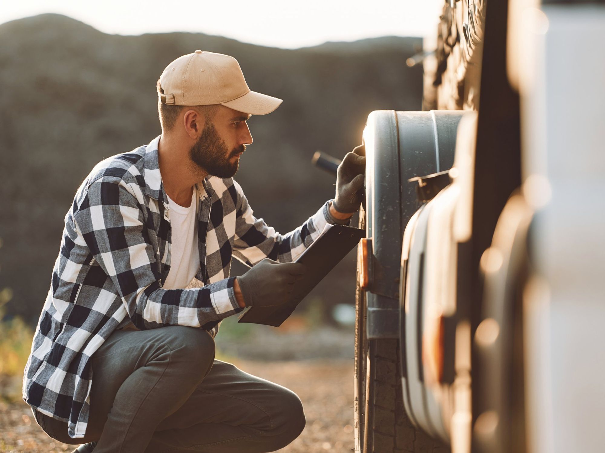 A truck driver inspects the front tires of his truck.