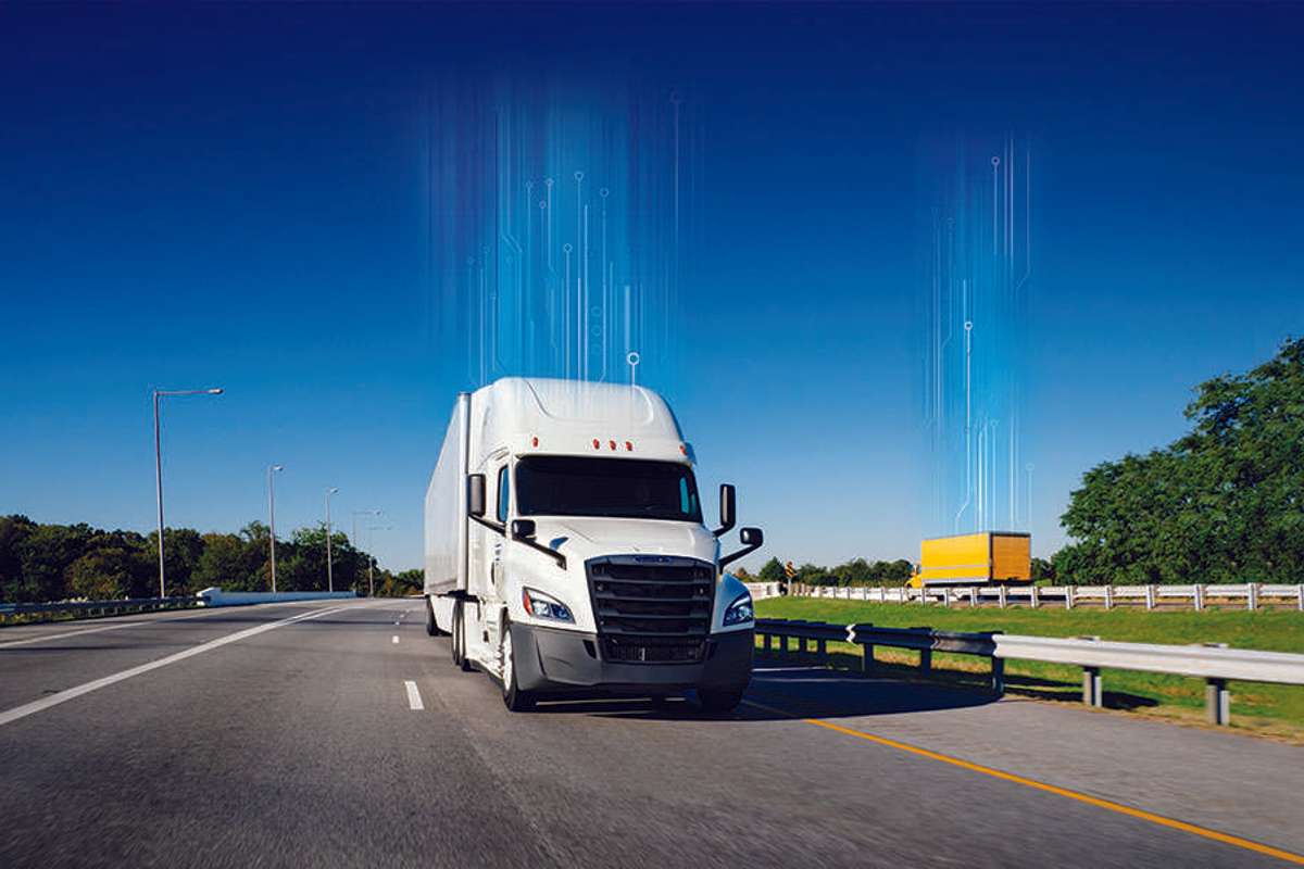 A white Penske semi-truck and yellow Penske box truck drive in opposite directions of a freeway.