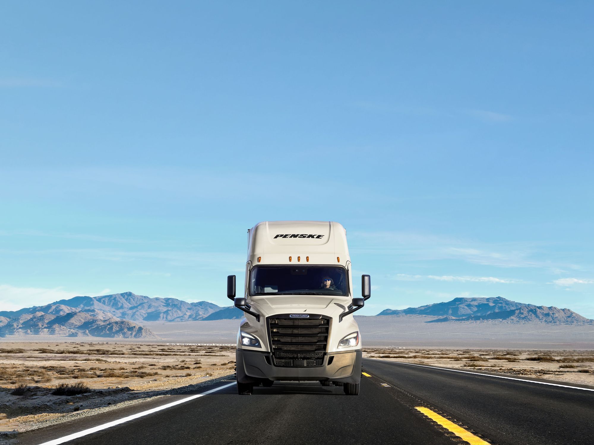 A white Penske truck on the road
