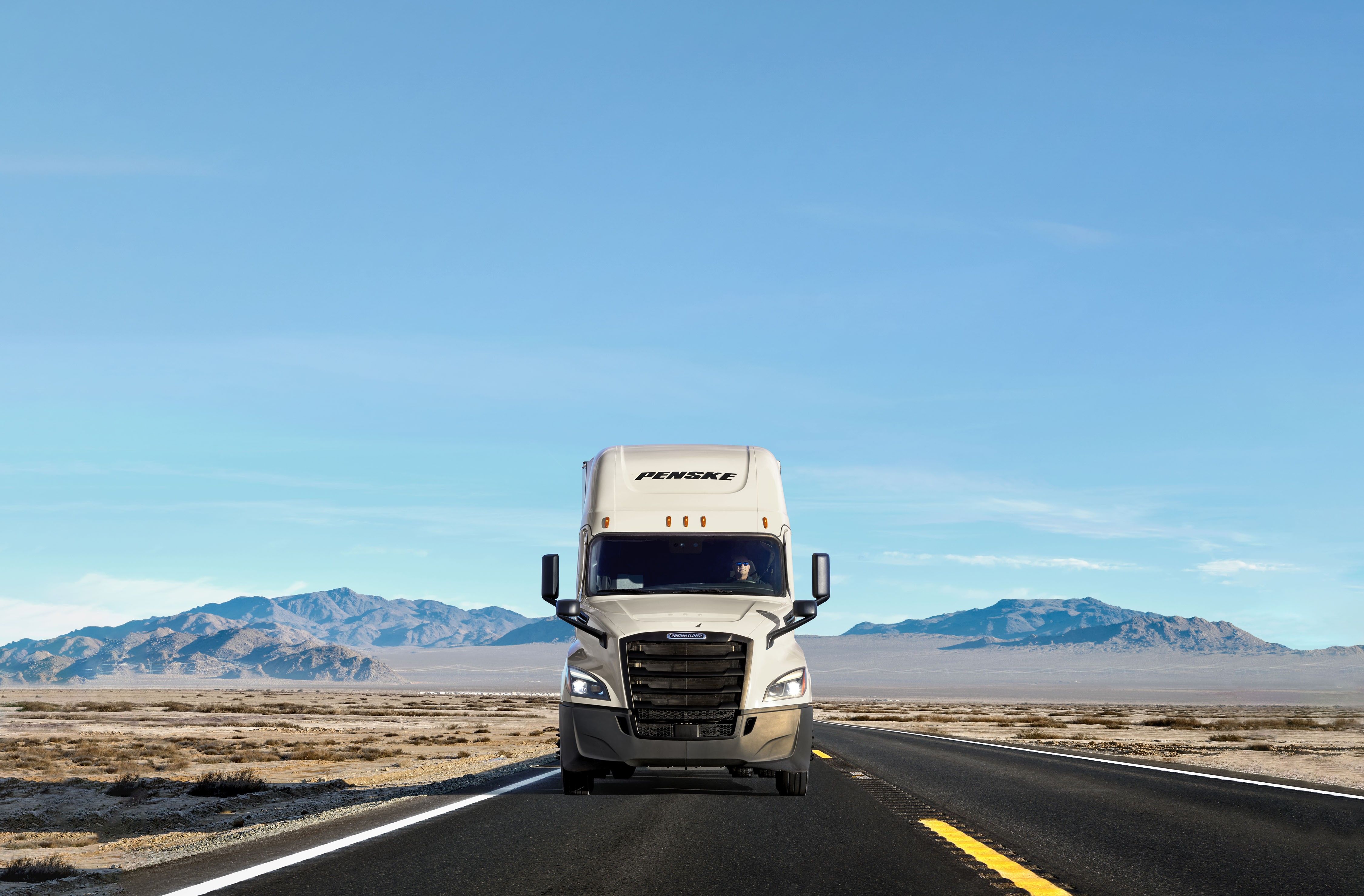 A white Penske truck on the road