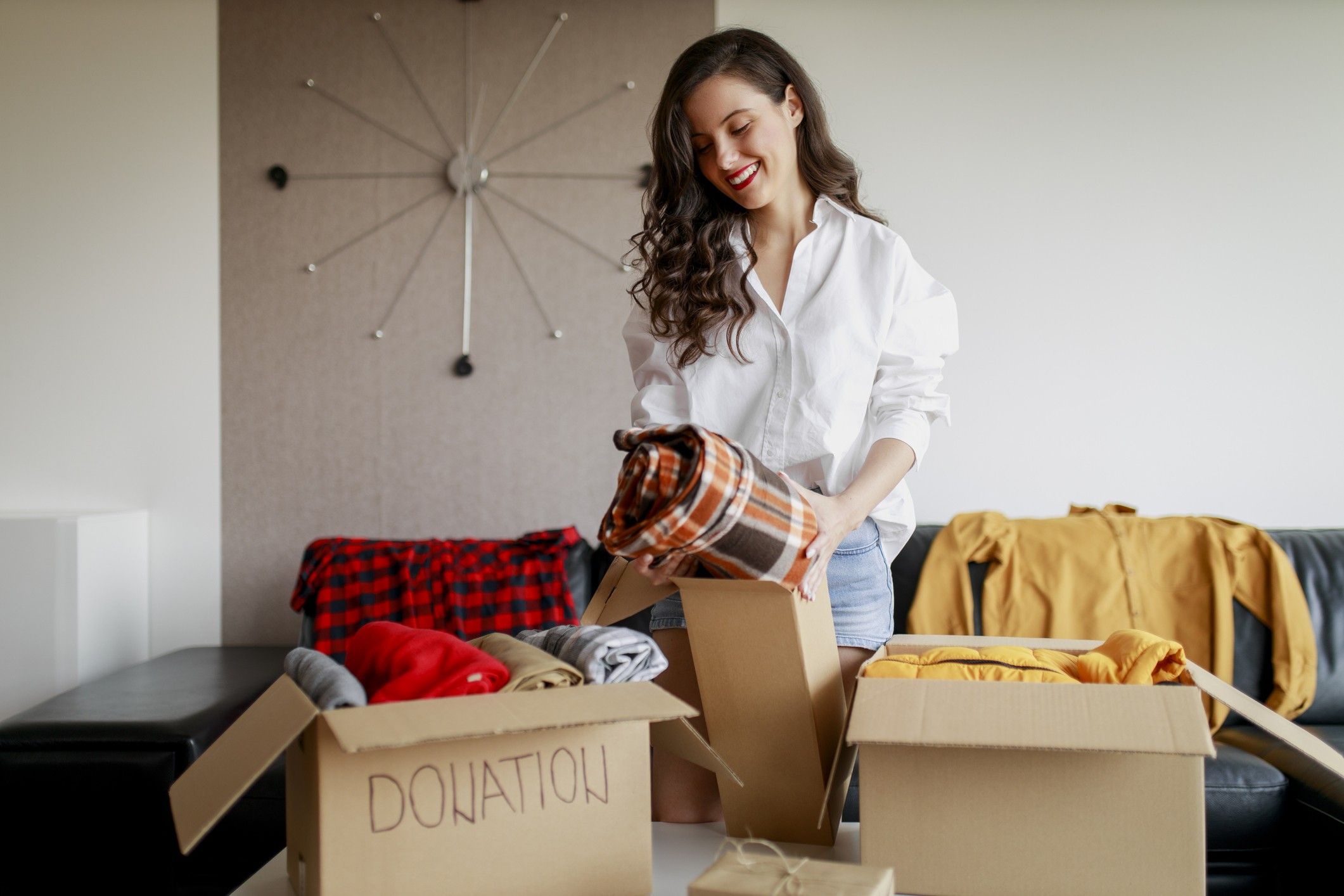 A woman declutters clothing into two boxes.
