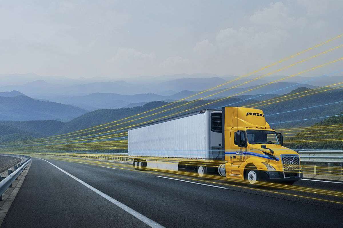 A yellow and white Penske semi-truck driving on a highway with a yellow digital overlay.