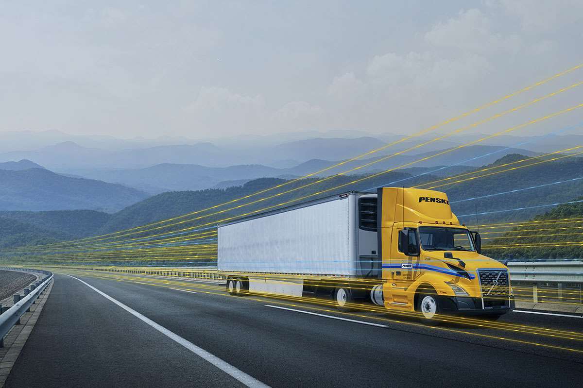 A yellow and white Penske semi-truck driving on a highway with a yellow digital overlay.
