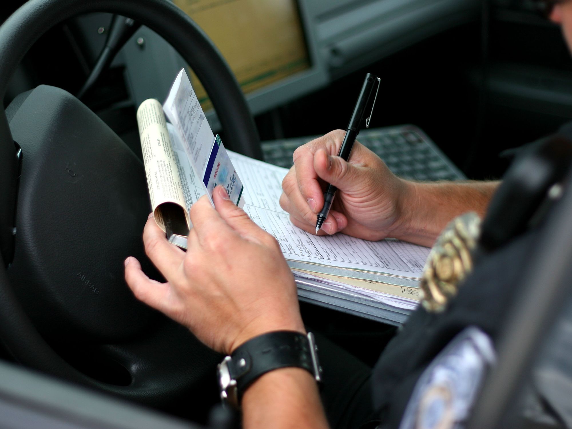 An officer writes out a citation while sitting in his car.
