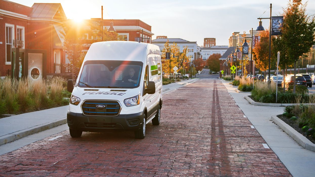 An Penske electric cargo van drives up a brick road in the city.