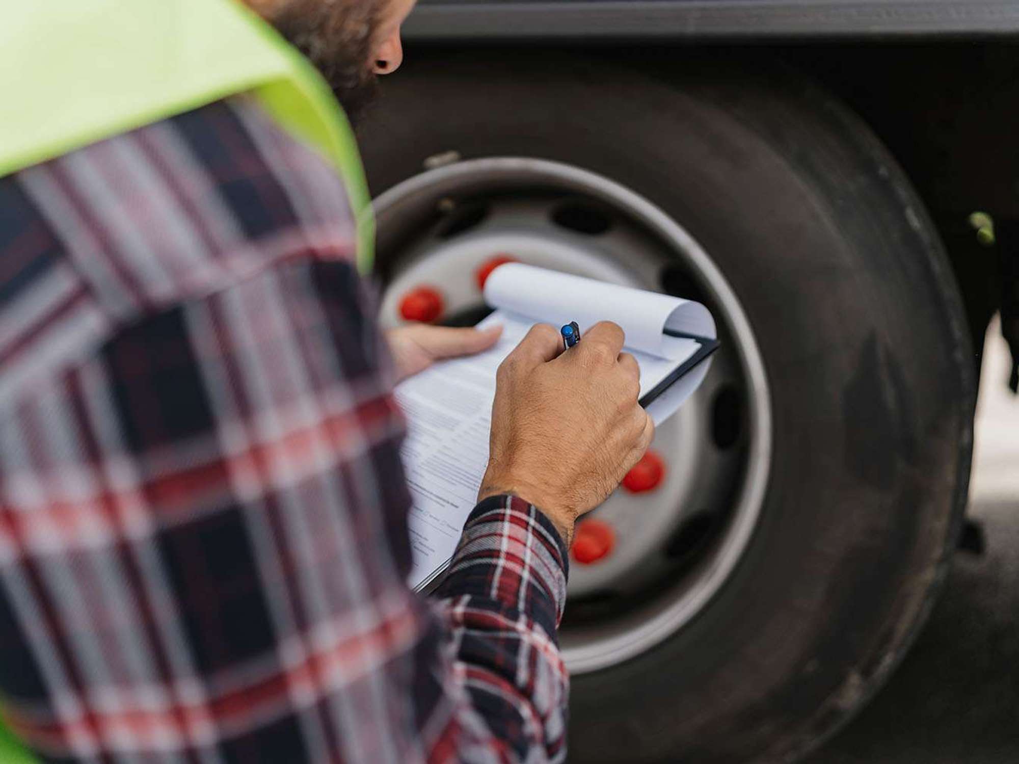 Close-up of a man holding a pen and paper checklist, making marks on the checklist.