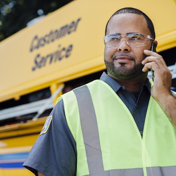 Customer service associate on cell phone in front of Penske vehicle