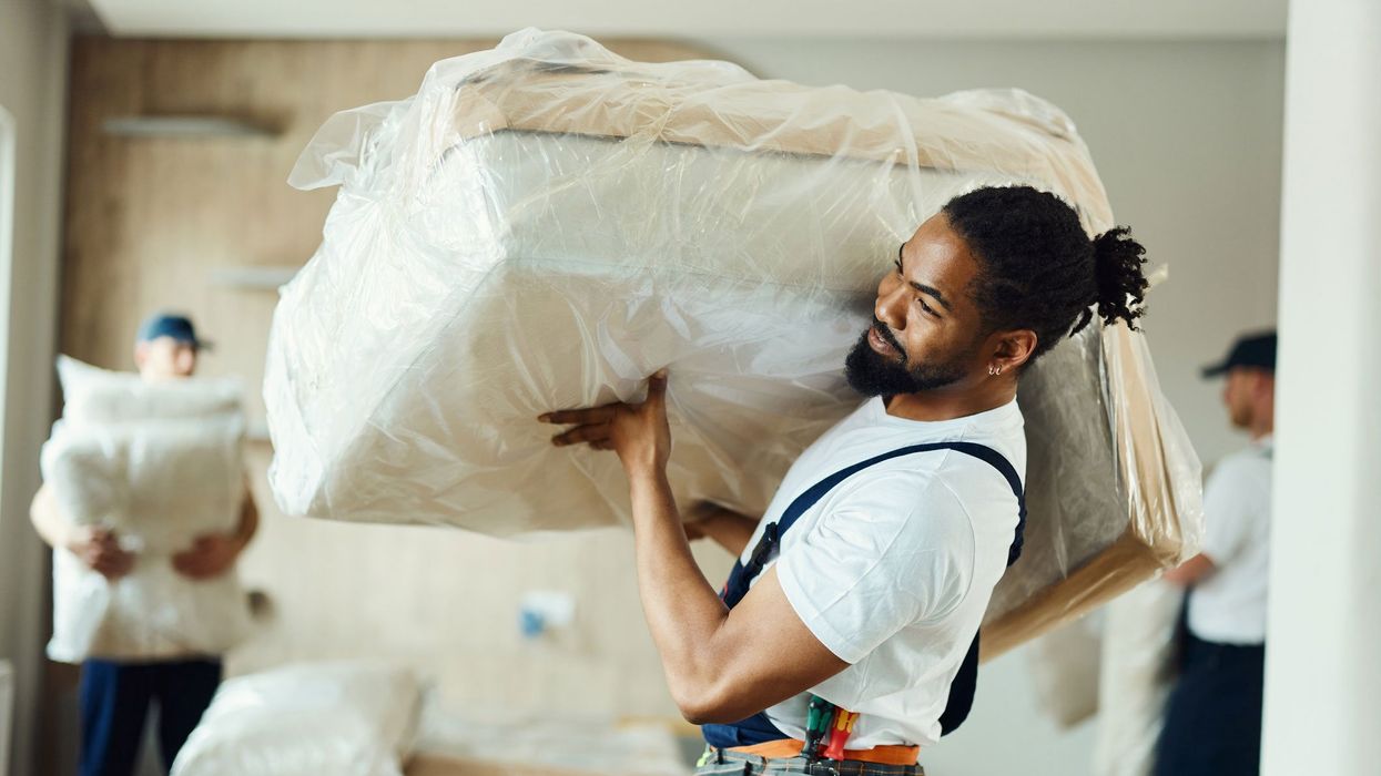 Moving man carrying furniture inside a home.