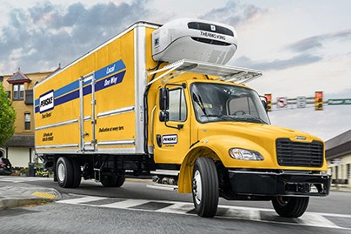 Penske refrigerated truck (CDL required) on a city street by a red brick building