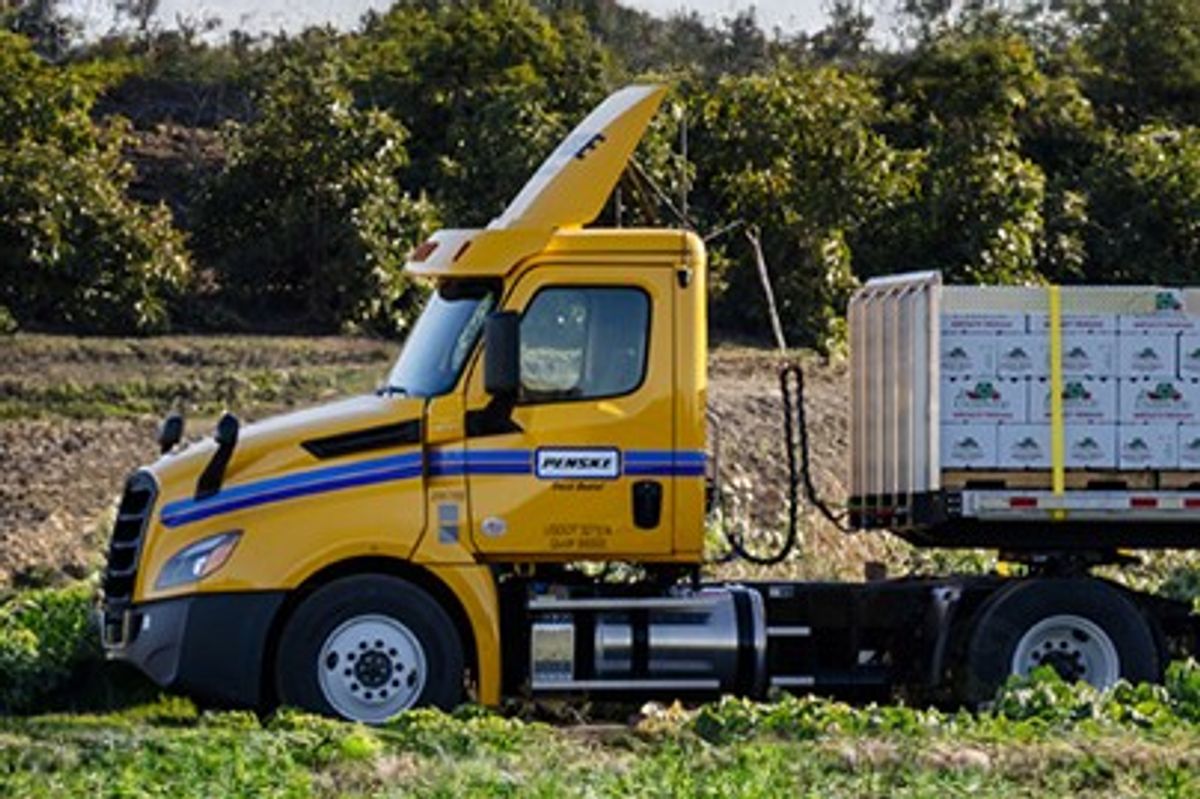 Penske single-axle day cab tractor in a green field