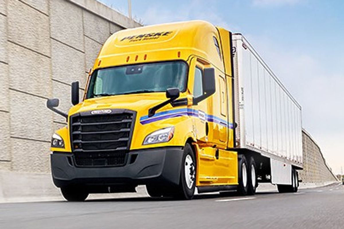 Penske tandem-axle sleeper tractor passing by a retaining wall