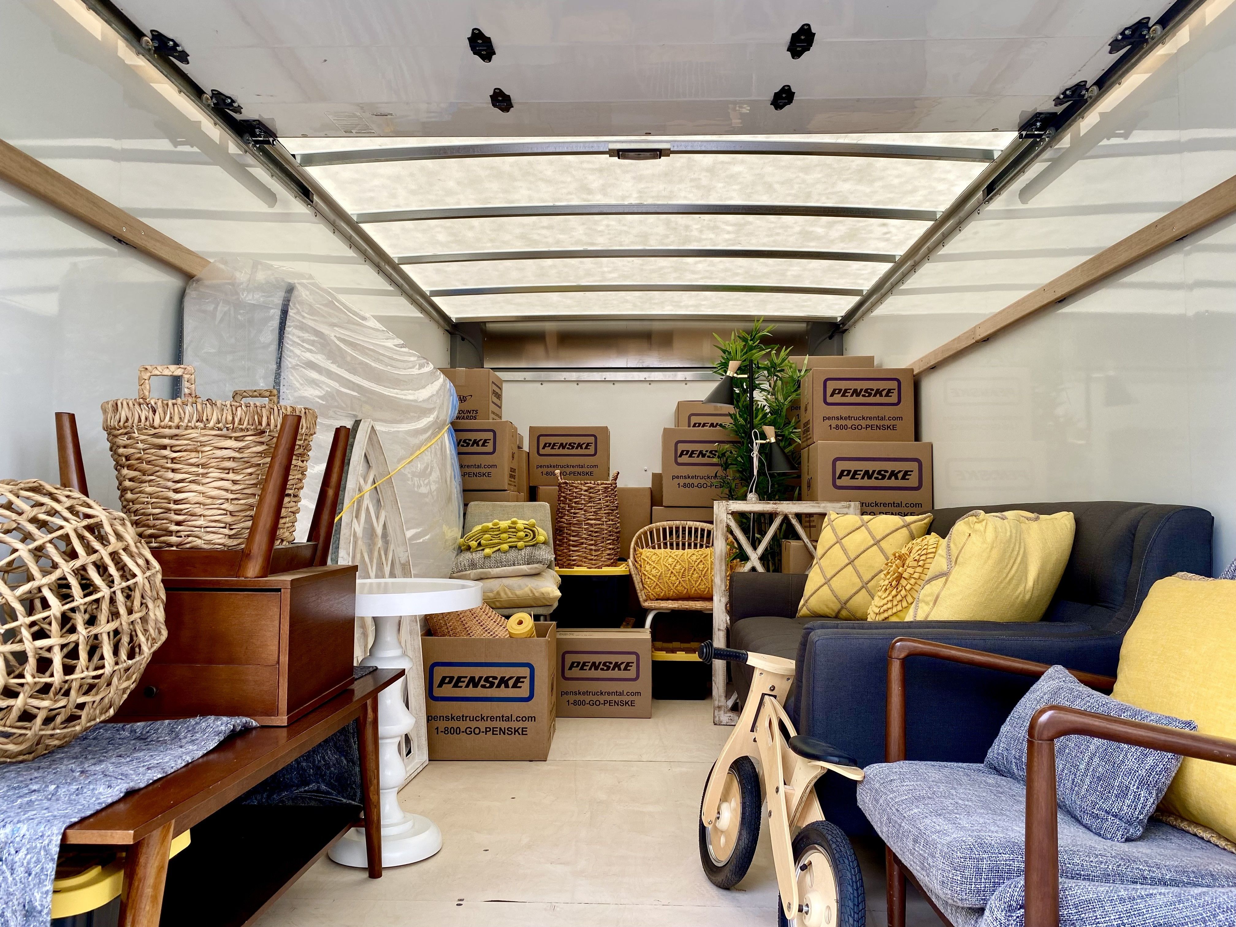 The inside of a moving truck filled with boxes, a couch, tables, a mattress and other family belongings.