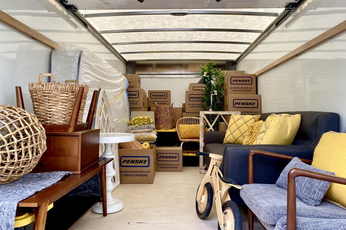 The inside of a moving truck filled with boxes, a couch, tables, a mattress and other family belongings.
