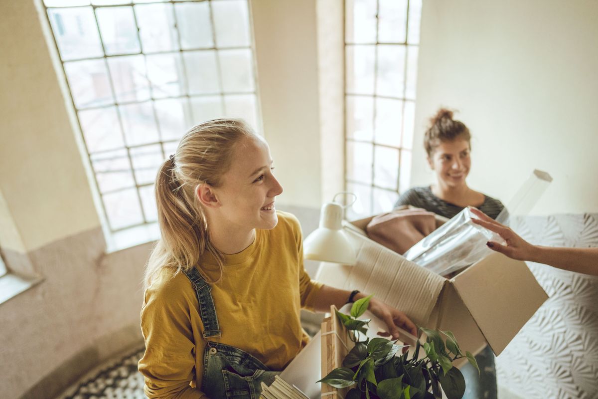 Two college students carry boxes up a set of steps.