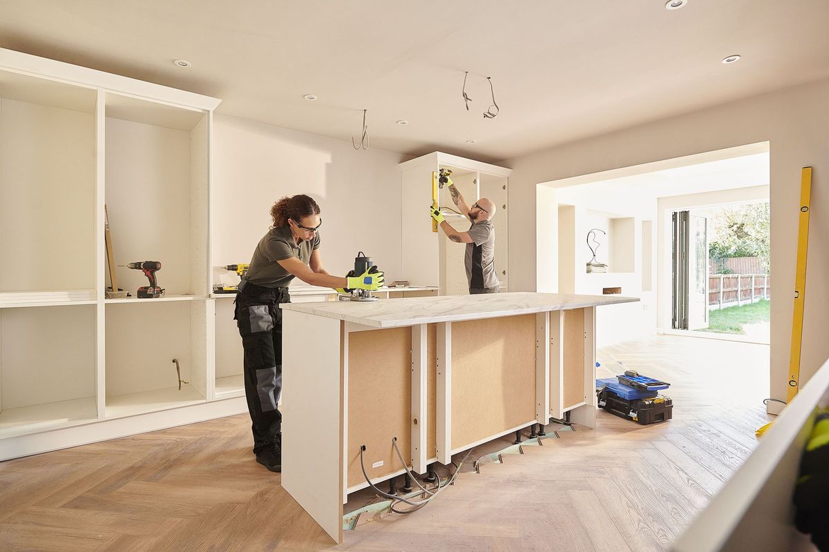 Two contractors work on installing a new kitchen.