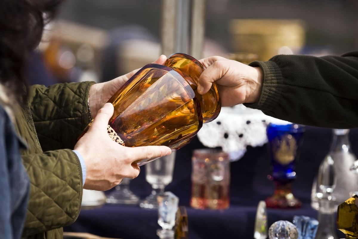 Two hands hold an amber-colored glass vase.