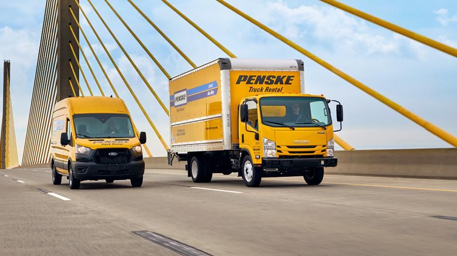 Two Penske trucks on a bridge.