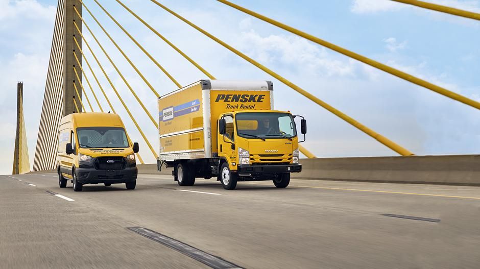 Two Penske trucks on a bridge.