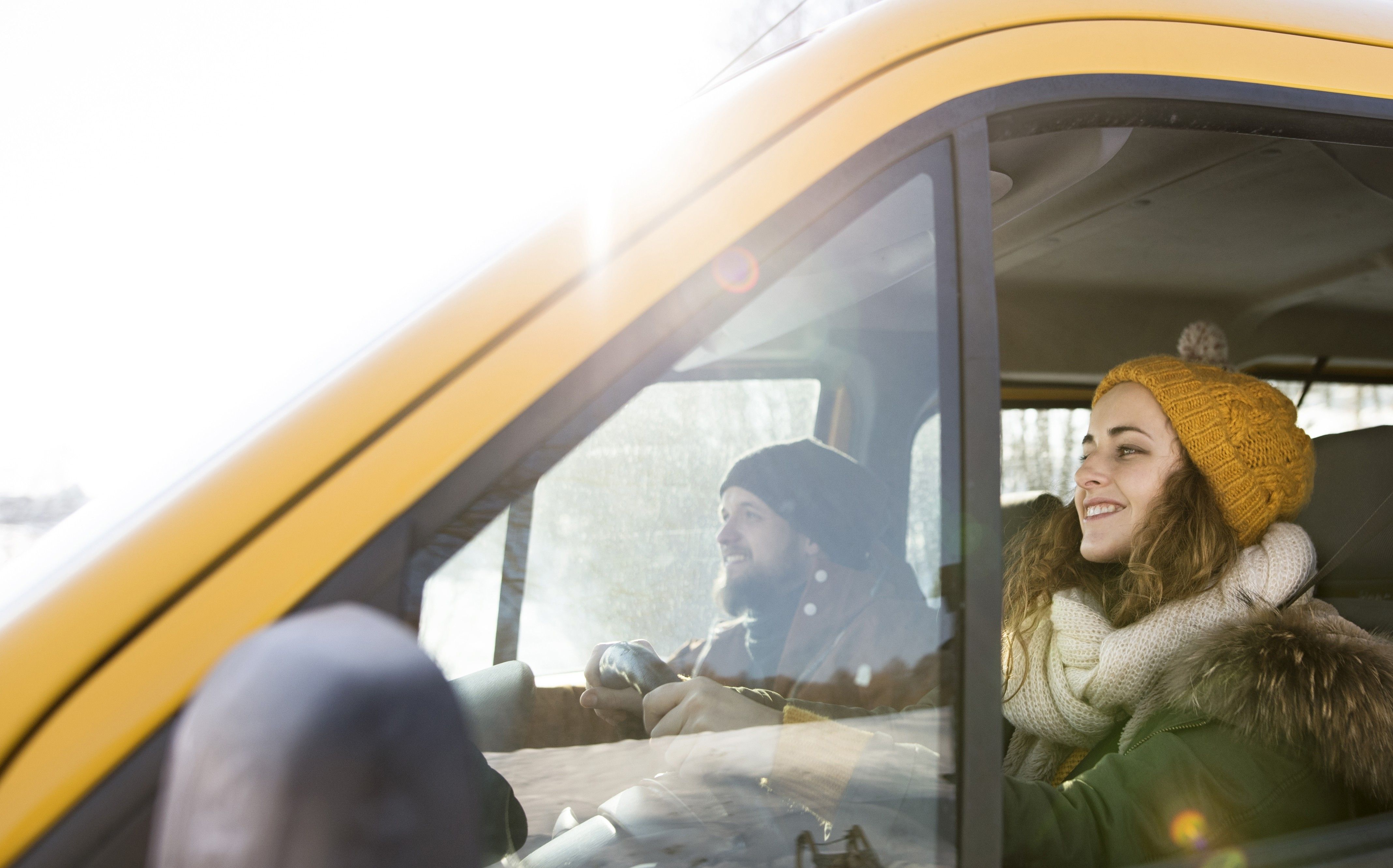 Two people drive in winter in a yellow moving van.