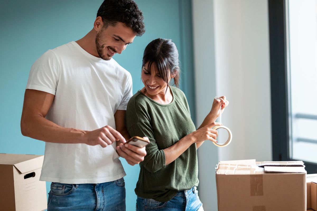 Two people look at a cellphone while packing