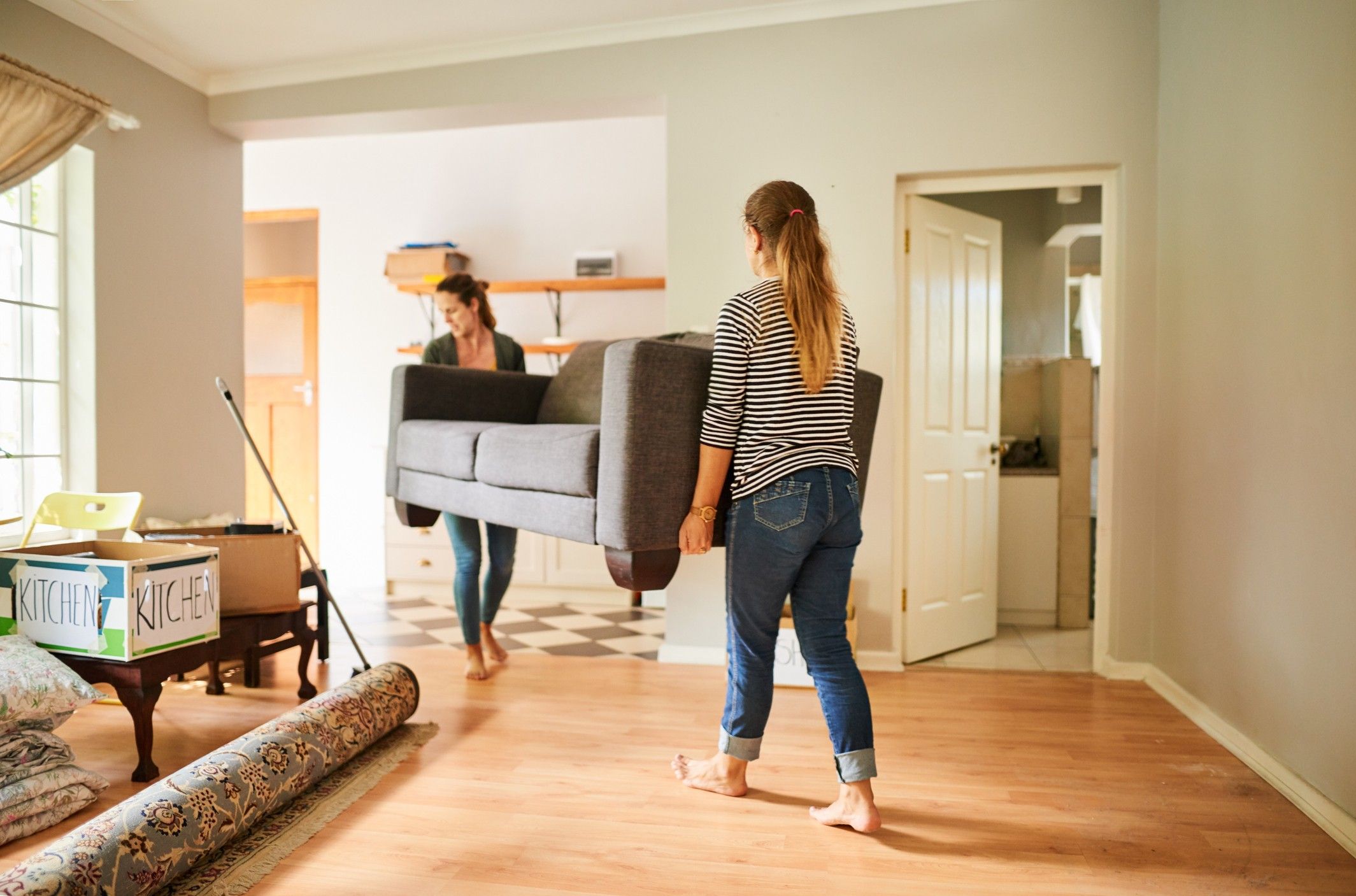 Two people move a couch in their new home.
