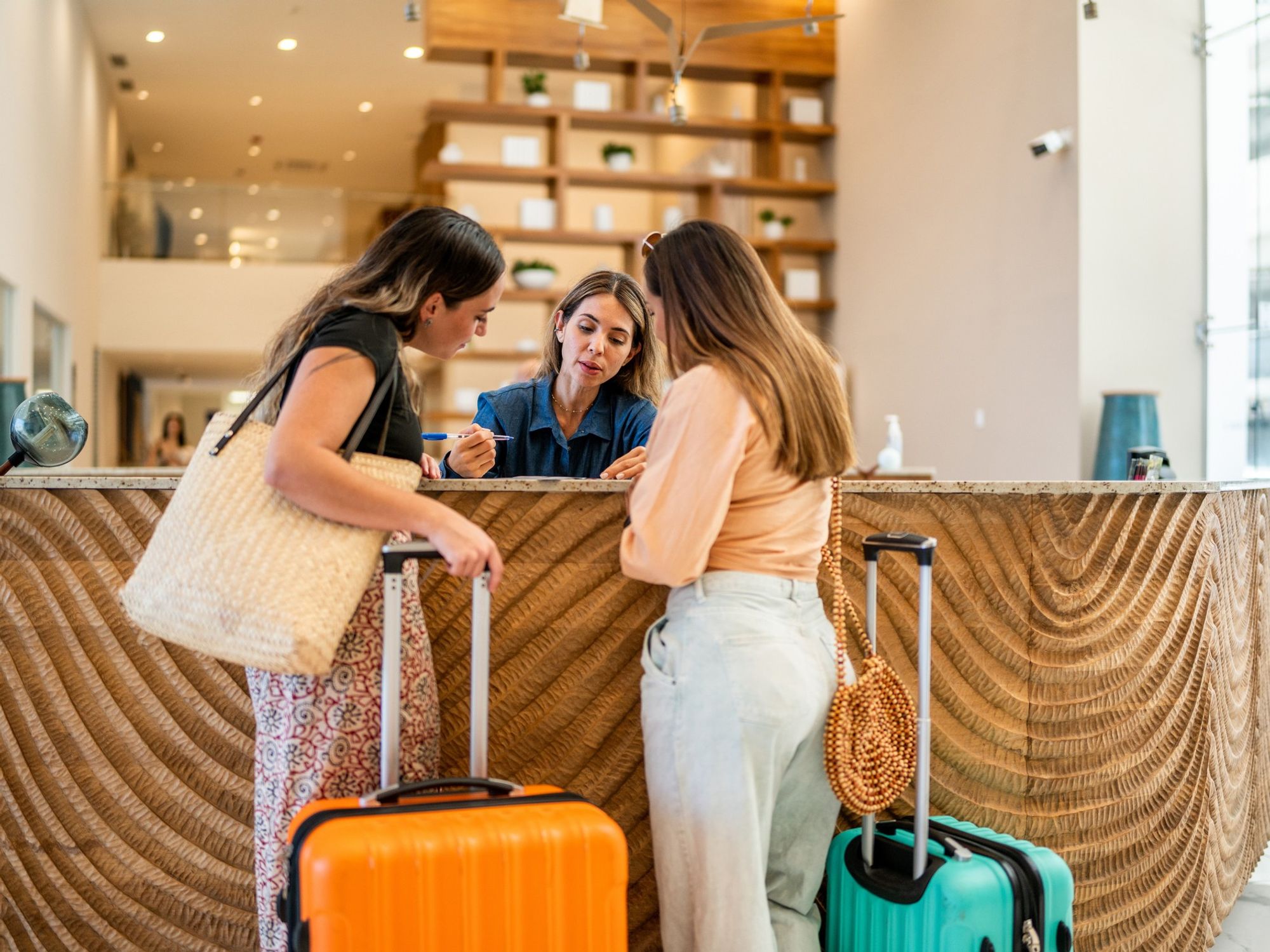 Two women check in at a hotel front desk.